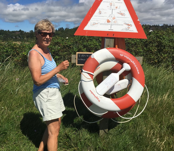 5. august 2016: Grundejerforeningen har denne sommer lanceret en ny service til glæde for badedyrene ved Hostrup Strand – nemlig en daglig melding om badevands-temeperaturen. Den nye service skyldes kvinden på billedet, Tove Hansen, der har påtaget sig at tage temperaturen på vandet og notere resultatet på en lille tavle ved redningsposten. (Foto: Jens Frede)